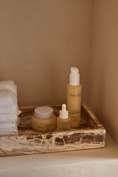 Anare Naturals Daily Essentials Bundle placed in the corner of a wall in an aesthetic bathroom with brown accents.