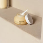 Anare Naturals Daily Moisturizer placed in the corner of an aesthetic light brown wall.