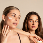 A blonde and brunette woman applying the Daily Moisturizer while holding the product, showcasing its lightweight texture and hydrating effect.