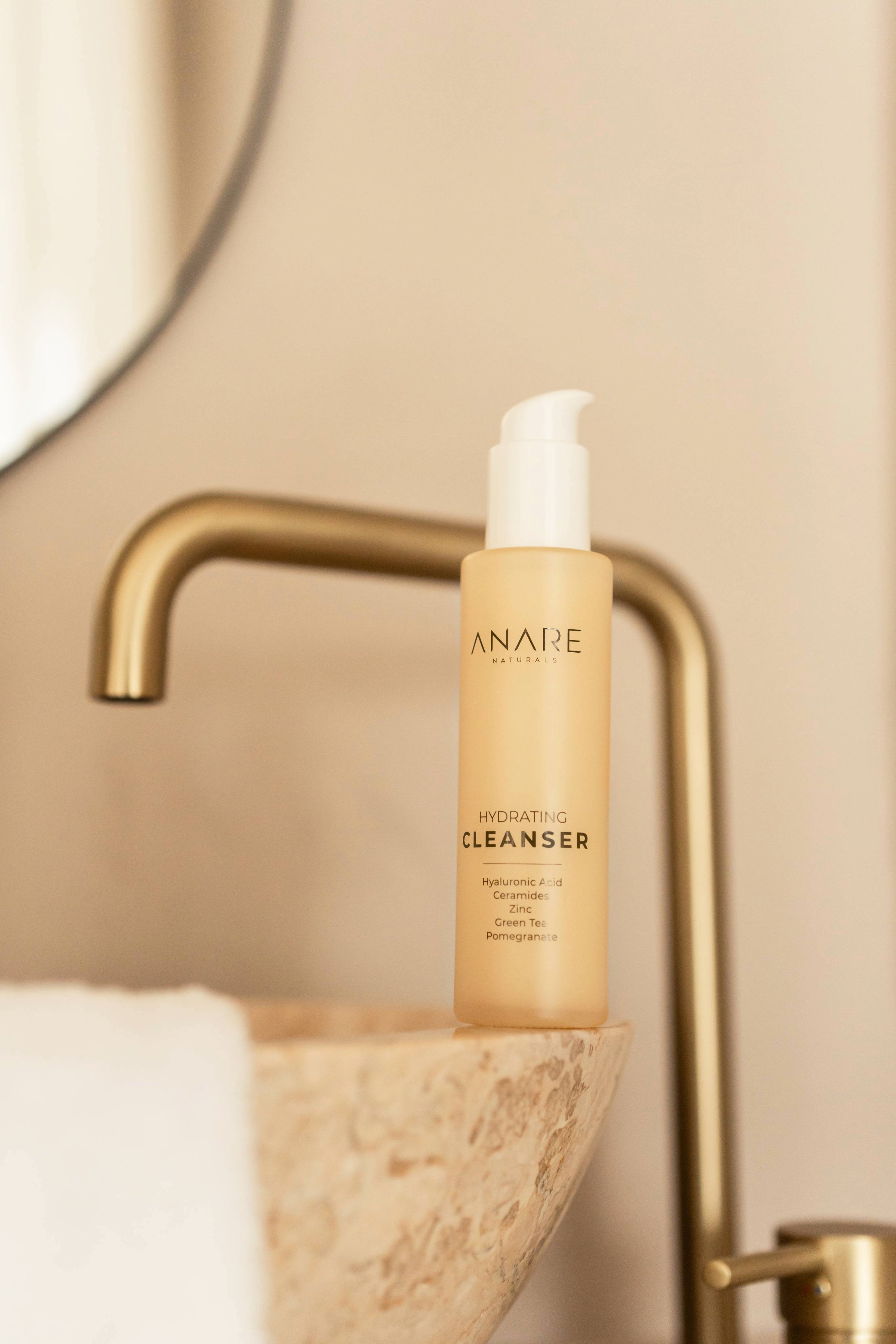 A sleek glass bottle of the Hydrating Cleanser resting on a bathroom sink, ready to refresh and cleanse your skin.