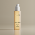 Hydrating Cleanser in a sleek glass bottle, displayed in a clear, sand-colored space, highlighting its minimal and refreshing skincare design.